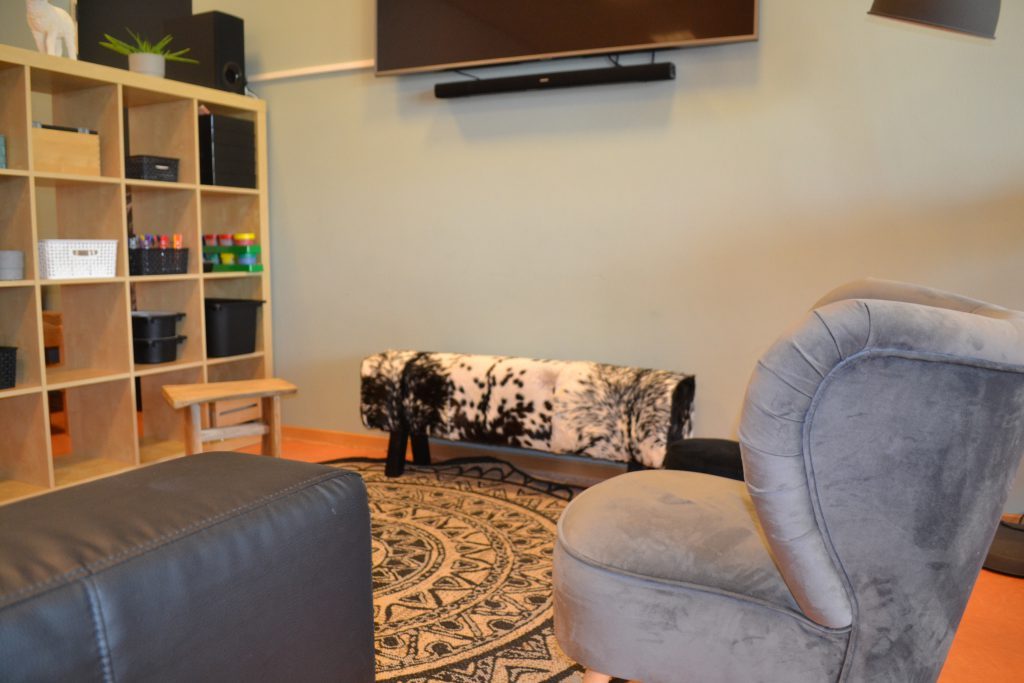 De chillhoek van de BSO met fauteuil, bank en een kast met spelletjes