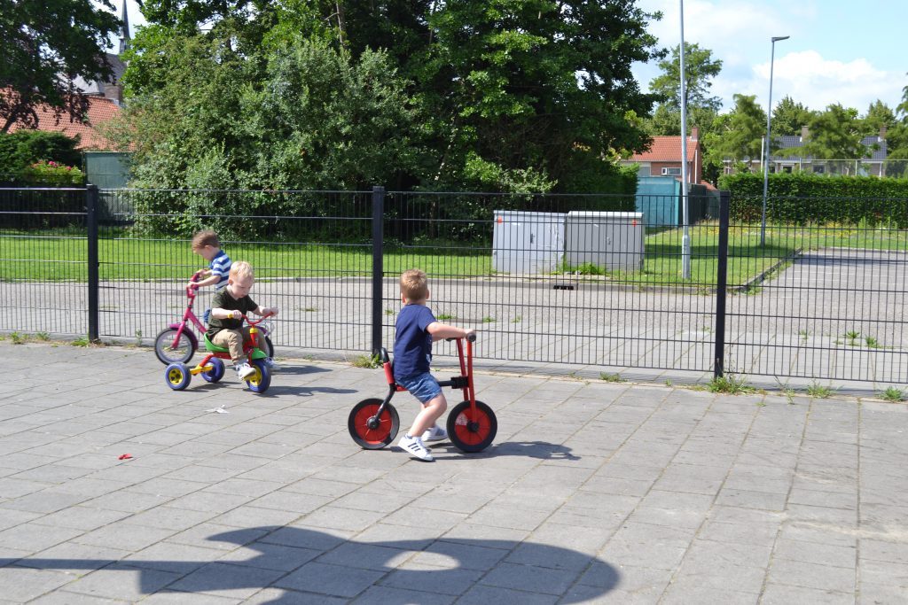 Peuters rijden op driewielers buiten