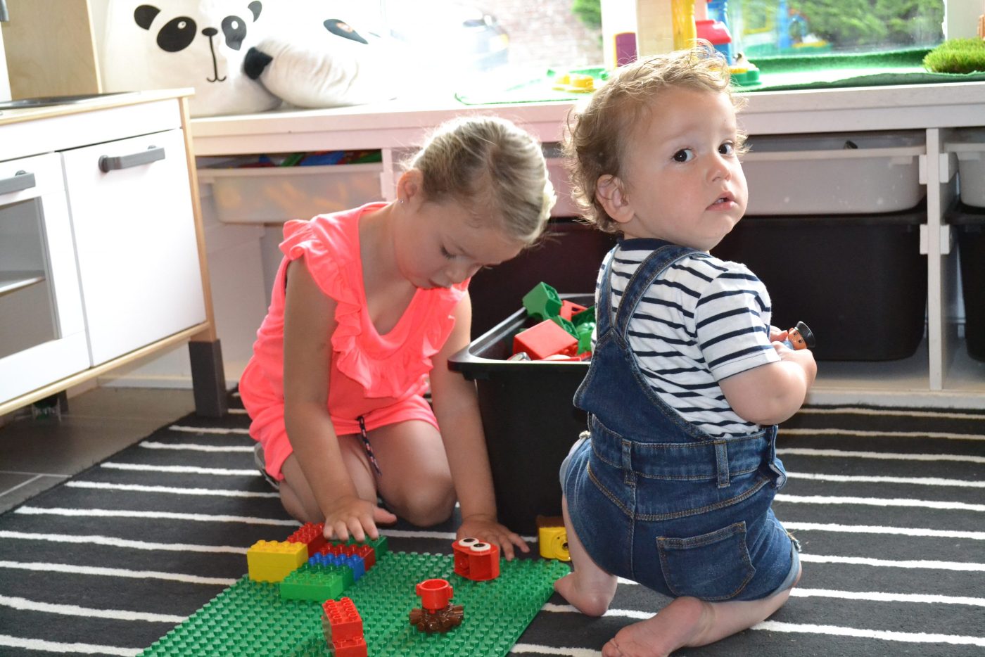 Een meisje en een dreumes spelen met Duplo op het kinderdagverblijf