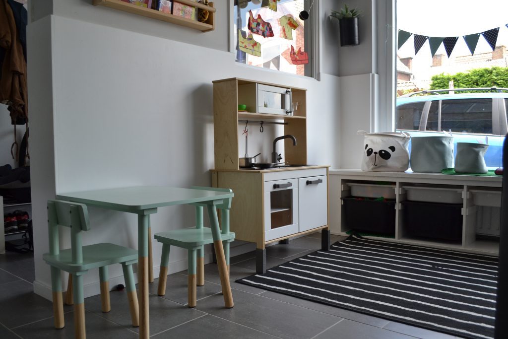 De groepsruimte met een kindertafeltje, speelkeuken en opbergbakken