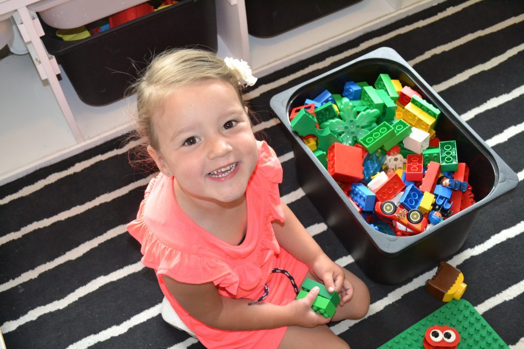 Lachend meisje naast een bak Duplo